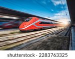 High speed train in motion on the railway station at sunset. Fast red modern intercity train and blurred background. Railway platform. Railroad in Italy. Commercial. Passenger railway transportation