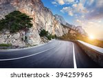 Beautiful winding mountain road with a perfect asphalt with high rocks and colorful sunset in summer. 