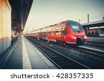Beautiful railway station with modern red commuter train at colorful sunset in Nuremberg   , Germany. Railroad with vintage toning