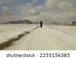 A person walks through a field filled with white snow.
