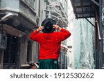 a girl in a red sweatshirt stands with her back with her hands holding a hat black on her head it's snowing on the background of the street. tourist Istanbul.