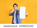 Small photo of image of asian man holding phone, isolated on yellow background
