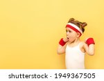 Small photo of Excited fitness child girl posing in sportswear,red wristbands,headband over yellow studio background. Children sport,advertising concept.Gym workout.Childhood activity.Sport.Health and energy