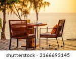 Small photo of Sea sunset in modern luxury restaurant with terrace. Outdoor restaurant at the beach with pair of chair. Table setting at tropical beach restaurant. Elegant hotel or resort restaurant.