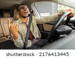 Joyful black man dancing in car ...