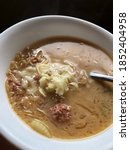 Small photo of Reuben soup with cheese on top in an elegant white bowl