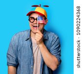Small photo of Young nerd man with noob hat holding an American flag on blue background