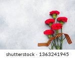 Red carnations and St. George ribbon on a concrete background. Symbol may 9, victory day. Copy space
