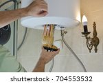 Plumber taking out an old water heater with scale deposition from a boiler in a bathroom