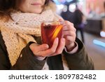 Close-up mug with mulled wine in woman hands, outdoor christmas evening market background