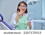 Small photo of Middle-aged female in dental office looking in mirror