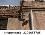 Small photo of Residential gas pressure regulator. old gas pressure regulator with rusty pipelines over a cement wall of a house. old rusty gas pipes. Pipeline Networks of Gas on the Street outside the house