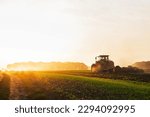 Small photo of a tractor in a field plows the ground at dawn, sowing grain. High quality photo
