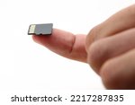 Selected focus on the SD card above the finger with a white background and blurred fingers.