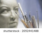 Sculpture tools in the art studio. Face of statue blurred against white background.