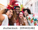 Friends in costumes have fun at carnival party in the street. Brazil holiday fun selfie with group of people together