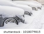 Small photo of Snow covered ows of cars in the parking lot. Urban scene, snowstorm. Clean automobile from the snow