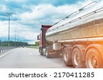 Small photo of Big metal fuel tanker truck shipping fuel on the countryside road against a cloudy sky
