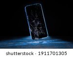 Mobile cellphone with broken glass. Smartphone falling down on the ground and broke touchscreen with beauty blue backlight and dark background