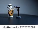 Small photo of Tangsel, Indonesia - May 27, 2021: firstorder trooper solo perform, play accoustic guitar and sing in lowkey shadow mode photo. lego minifigs are made by the LEGO group