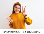 Young beautiful woman wearing yellow sweater and diadem over isolated white background smiling looking to the camera showing fingers doing victory sign. Number two.