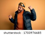 Young handsome skier man with beard wearing snow sportswear and ski goggles Dancing happy and cheerful, smiling moving casual and confident listening to music
