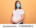 Young pregnant woman mother to be wearing protection mask for coronavirus disease looking to side, relax profile pose with natural face and confident smile.