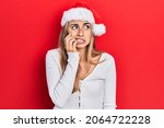 Beautiful hispanic woman wearing christmas hat looking stressed and nervous with hands on mouth biting nails. anxiety problem. 