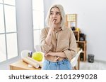 Young beautiful caucasian woman at construction office looking stressed and nervous with hands on mouth biting nails. anxiety problem. 