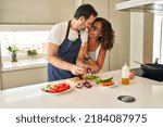 Middle age hispanic couple smiling confident and hugging each other cooking at kitchen
