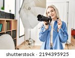 Beautiful blonde woman working as professional photographer at photography studio. Standing holding sdxc storage memory card