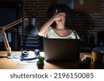 Small photo of Young brunette woman with curly hair working at the office at night covering eyes with hand, looking serious and sad. sightless, hiding and rejection concept