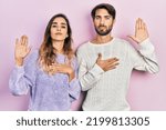 Small photo of Young hispanic couple wearing casual clothes swearing with hand on chest and open palm, making a loyalty promise oath