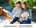 Man and woman holding dog having video call by touchpad at park