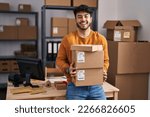 Small photo of Hispanic man with beard working at small business ecommerce holding packages celebrating crazy and amazed for success with open eyes screaming excited.