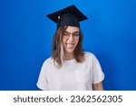 Blonde caucasian woman wearing graduation cap sticking tongue out happy with funny expression. emotion concept. 