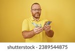 Small photo of Cheerful caucasian man confidently counting handsome sum of australian dollars, exuding positivity over an isolated, sunny yellow background