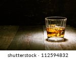 Scotch on wooden background with copyspace. An old and vintage countertop with highlight and a glass of hard liquor