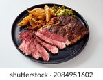 Small photo of High angle of palatable grilled beef steak and potatoes wedges served with green salad on plate on white background