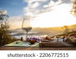 A red win glass and a cheese plate at beautiful sunset. An outdoor romantic picnis.