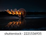 Woman posing for lightpainting photos with bright lights in the dark. Reflection in the water