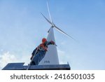 worker in Personal Protective Equipment work with wind turbine farm.  people in Safety Harness work on wind mill.
