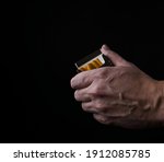 Small photo of Hand holding a pack of cigarettes offering a smoke. Isolated on black background.