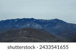 Small photo of Mountain range with specks of ice and greenery carpeting the mountains. Moody skies annotate the beautiful view of the mountains.