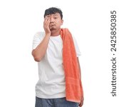 Small photo of Indonesian man has just woken up, still sleepy and yawning, going to take a shower. Asian man with orange towel wants to take a shower, still sleepy and yawning. Man with towel.