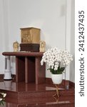 Small photo of Bandung, Indonesia - Dec 02, 2023: Gold color communion cupboard to put set of communion with angel decoration and white orchid