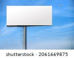 Billboard outdoor advertising, mockup billing board in front of a blue sky with a flying plane near the airport. Blank white background for branding design large hoarding