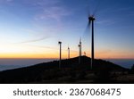 Windmills for electric power production on a mountain ridge early in the morning