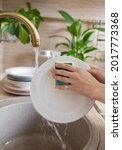 Small photo of women's hands wash dishes in kitchen sink, woman cleans kitchen and washes dishes, wash plates with foam from dishwashing detergent, house cleaning, taking care of cleanliness, maid or attendant