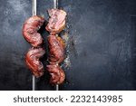 Small photo of Barbecue dry aged wagyu Brazilian picanha from the sirloin cap of rump beef sliced and offered as top view on a skewer on a rustic old board with copy space right